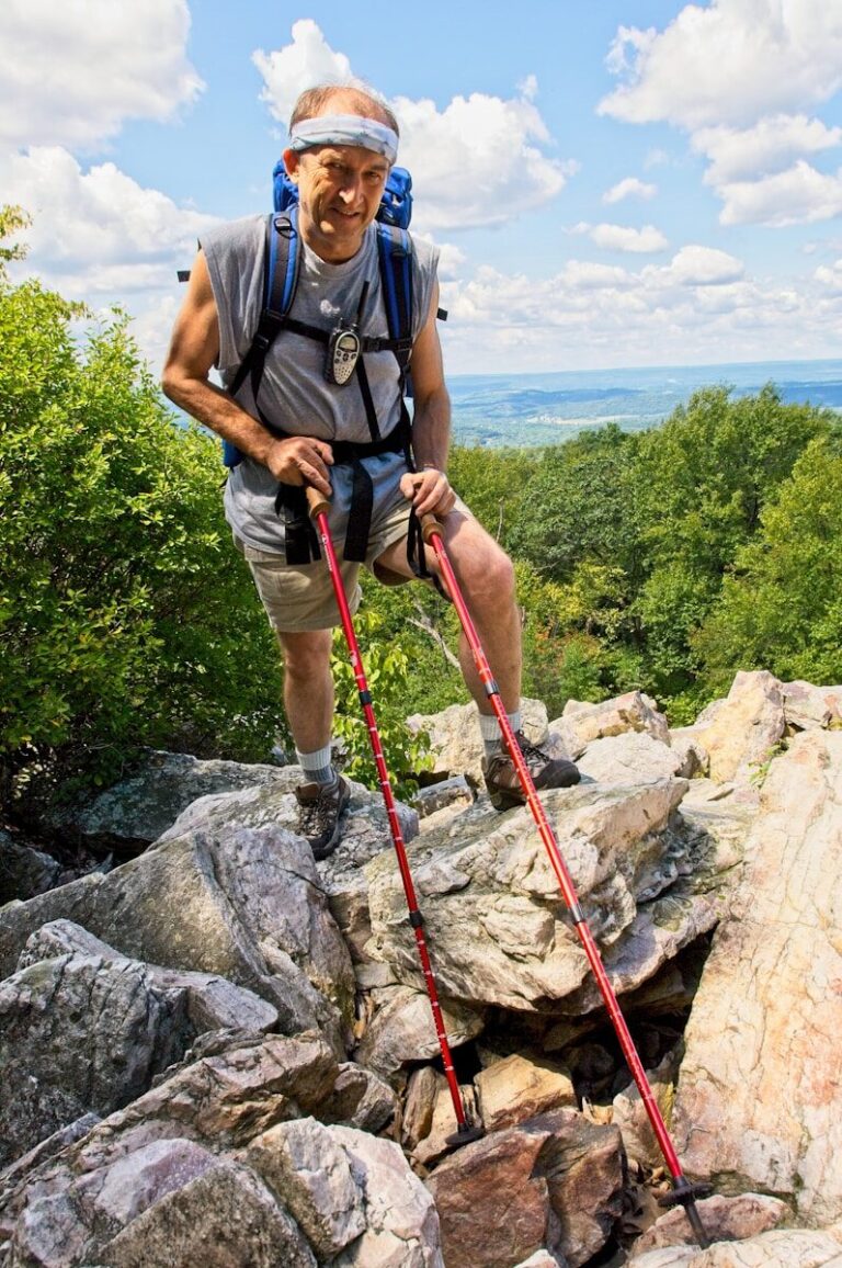 man in black t-shirt and blue denim shorts climbing on rocky mountain during daytime