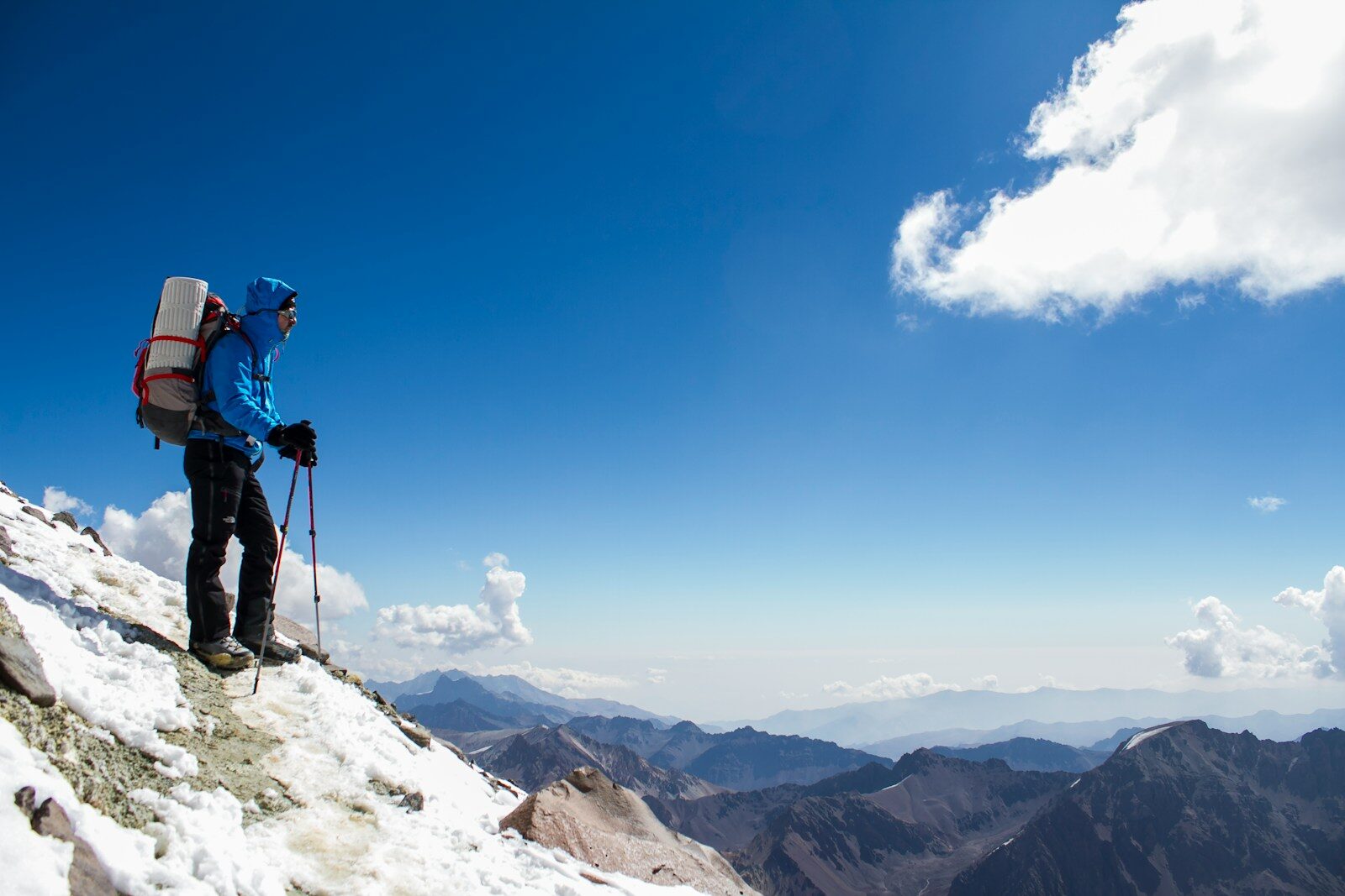 A man with a backpack is hiking up a snowy mountain